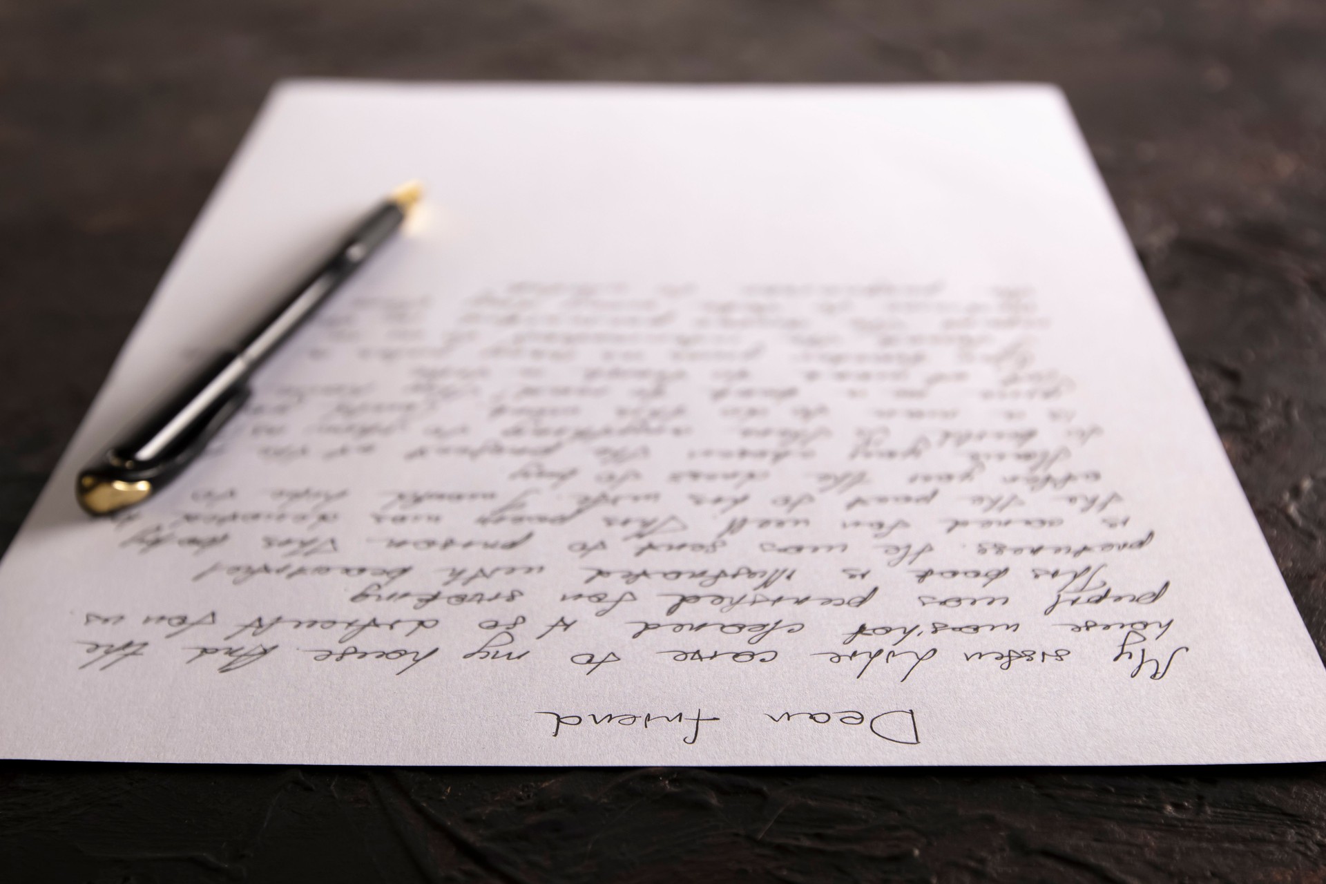 A letter written on paper lying on a table with a pen.