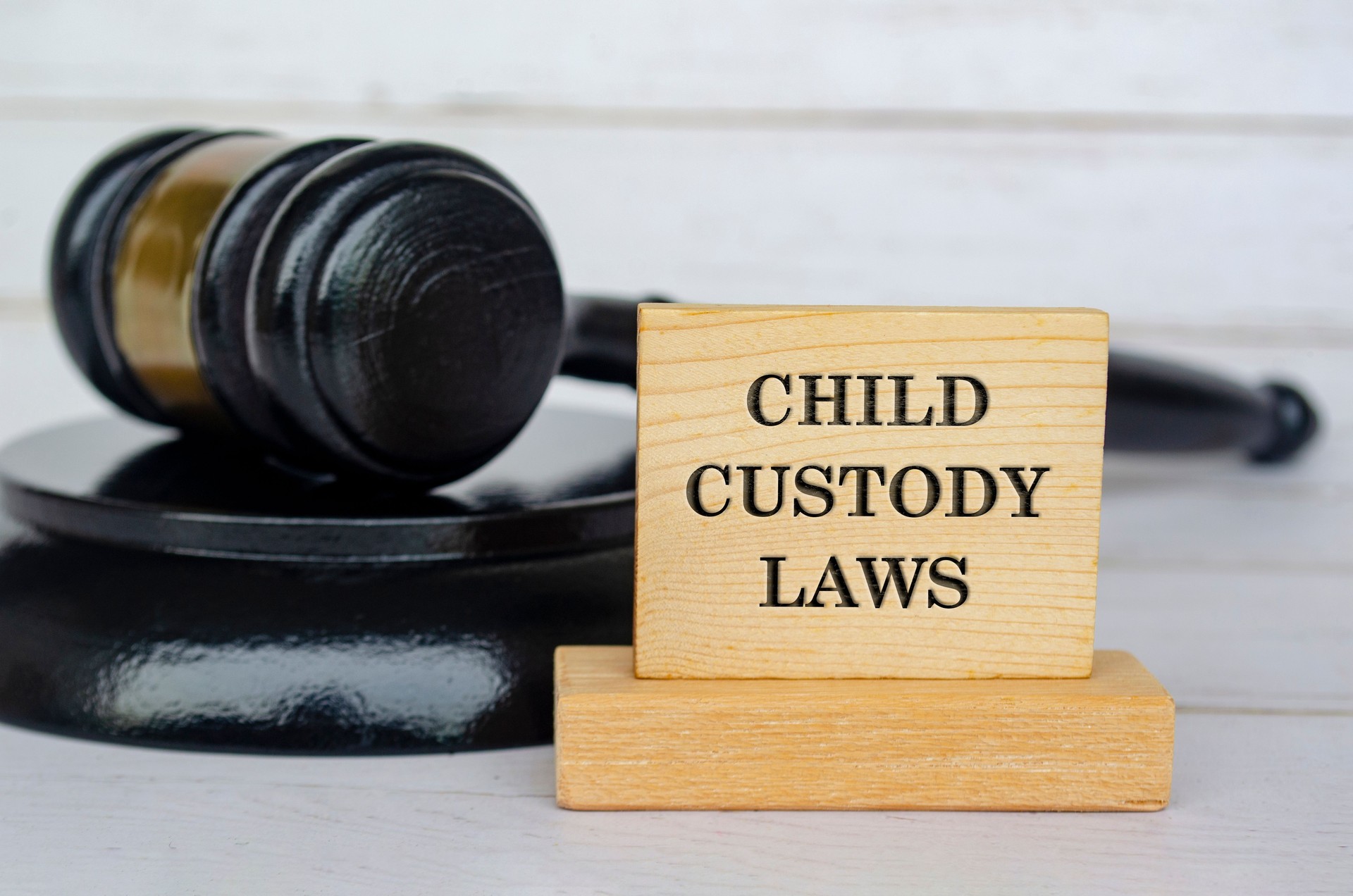 Child Custody Laws text engraved on wooden blocks with gavel background. Child custody concept